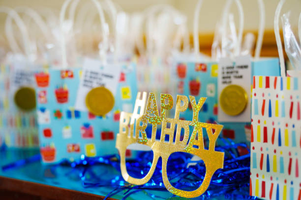 Various blue and gold birthday decoration and gift bags are set on a table during a home birthday party.