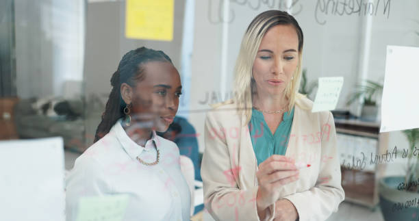 istock Business women, planning and notes with discussion at board for creative job and work. Collaboration, teamwork and communication with project management together in a office with copywriter staff 2151345850