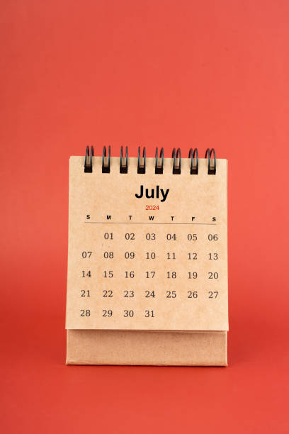 July 2024 white mini desk calendar on red background.