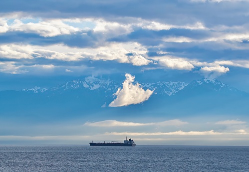 Oil tanker travels east as it passes the Olympic Mountains along the Strait of Juan de Fuca, Vancouver Island, British Columbia