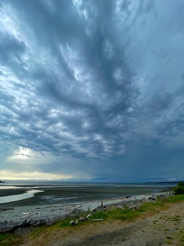 Ominous clouds over Juan de Fuca Strait signal the arrival of a rain squall, Whitty's Lagoon, Vancouver Island, British Columbia