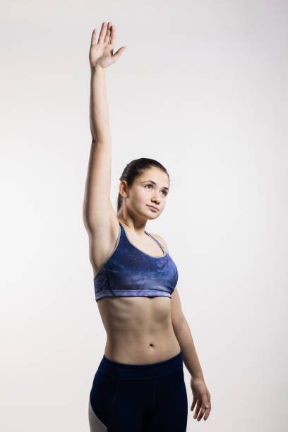 istock Young female athlete in sports outfit stretching in studio setting 2151352575