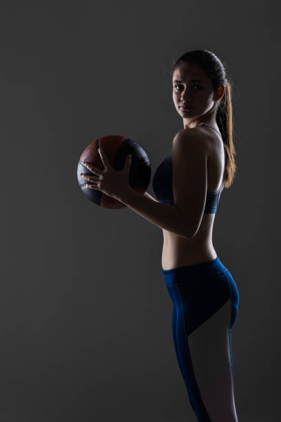 istock Confident young female basketball player holding a ball in studio setting 2151352606