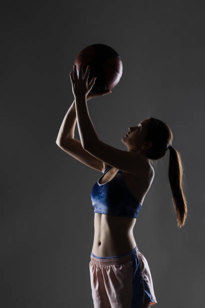 istock Young female athlete shooting basketball in dramatic lighting 2151352637