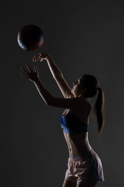 istock Young female athlete reaches elegantly for a basketball in a dramatic pose 2151352661