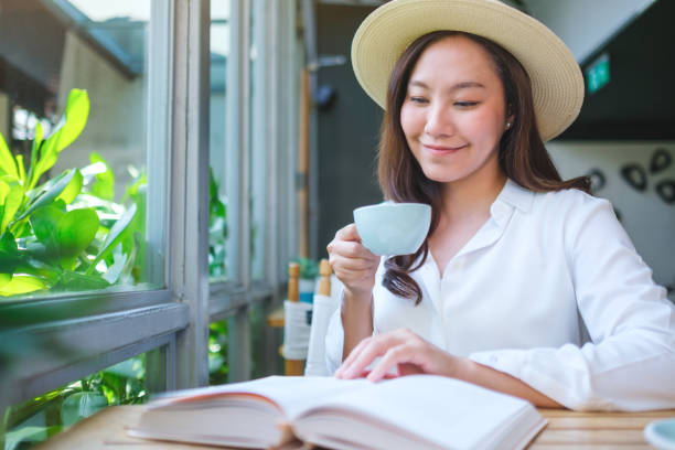 istock Portrait image of a beautiful young woman with hat drinking coffee while reading book 2151360316