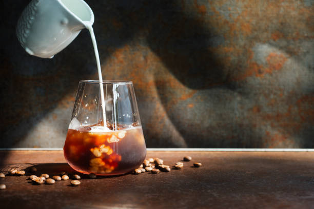 istock milk pouring into iced cold brew coffee  glass. 2151364501