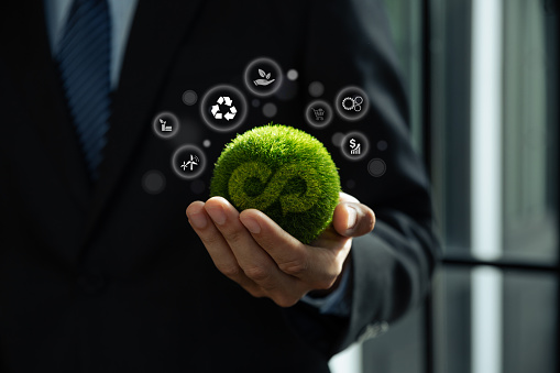 Hand of businessman holding green globe with circular economy icons, Circulating in an endless cycle, Business and world sustainable environment concept.