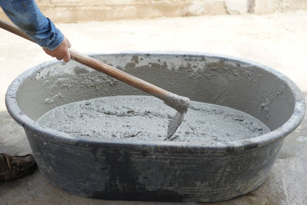 istock Close up worker using a hoe to mix cement powder, sand, stones in basin for mixing cement. Concept. Construction worker job. Hard working. Process of construction work with cement 2151365210