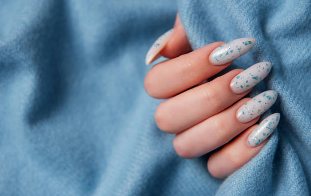 istock Female hands with blue nail design on blue textile background. 2151371578