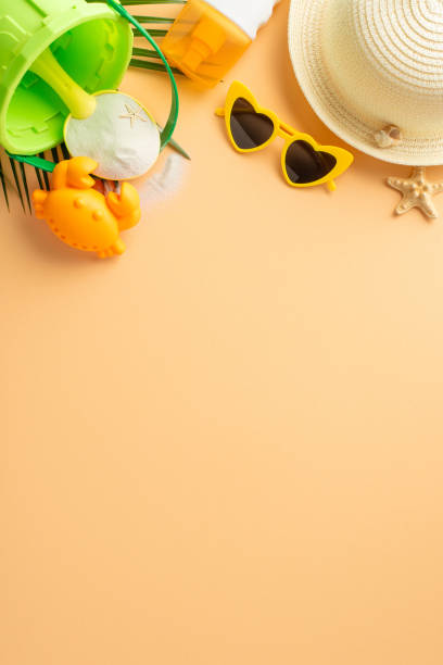 istock A collection of summer beach essentials arranged on a vertical sandy background, including a straw sunhat, yellow sunglasses, and colorful beach toys 2151372344
