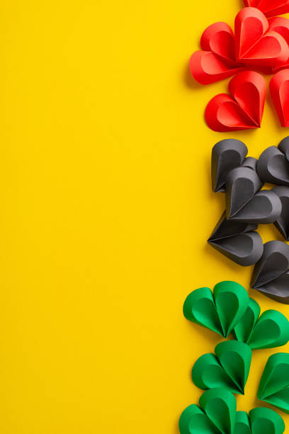 istock Vertical array of red, black, and green paper hearts arranged artistically on a yellow surface reflecting the themes of unity and celebration for Juneteenth 2151372350