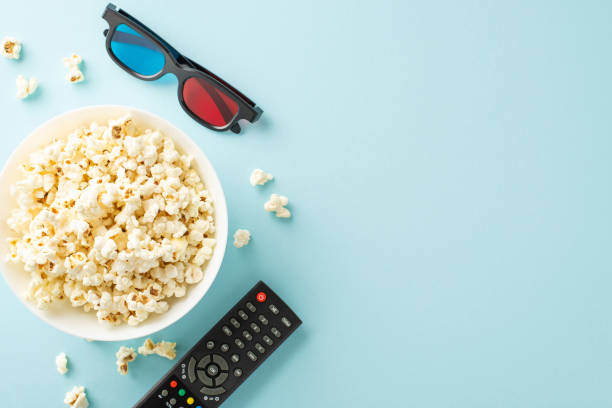 istock Create your own home theater with popcorn. Complete with 3D glasses, and remote control against a pastel blue backdrop. Top view, perfect for movie buffs 2151372377