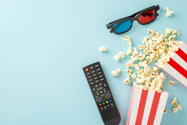 Elevate your movie night: top view of popcorn, 3D glasses, and streaming remote. Movie-themed decorations on a pastel blue backdrop, creating cozy atmosphere for unforgettable home cinema experience eleva tu noche de cine: vista superior de palomitas de maíz, gafas 3d y control remoto de transmisión. decoraciones con temática de películas sobre un fondo azul pastel, que crean un ambiente acogedor para una experiencia de cine en casa inolvidable