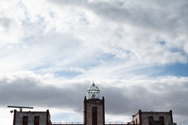 A large building with a tall tower and a dome on top. The sky is cloudy and the sun is not visible