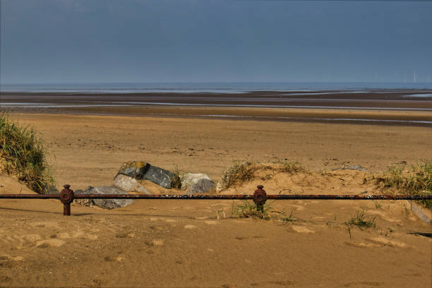 An old rusty pipe running along a nice beach. Taken on a cloudy day.