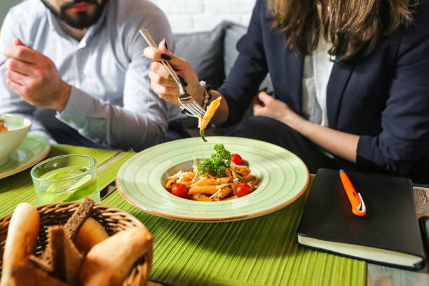 A man and woman are seen happily eating a meal at a table.