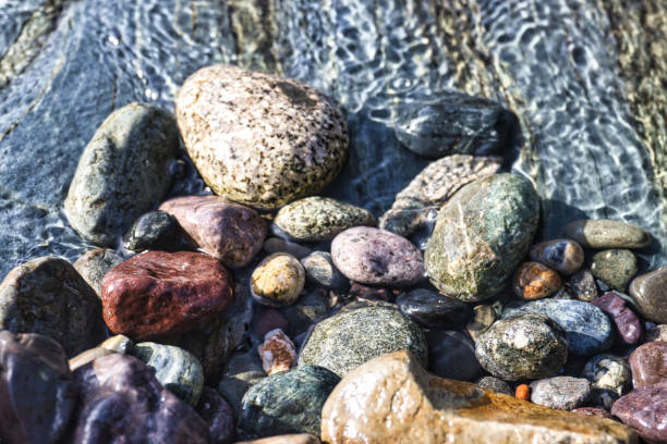 Siola - France. March 19, 2024. Close-up view of colorful pebbles lining the bottom of a mountain stream in Corsica.