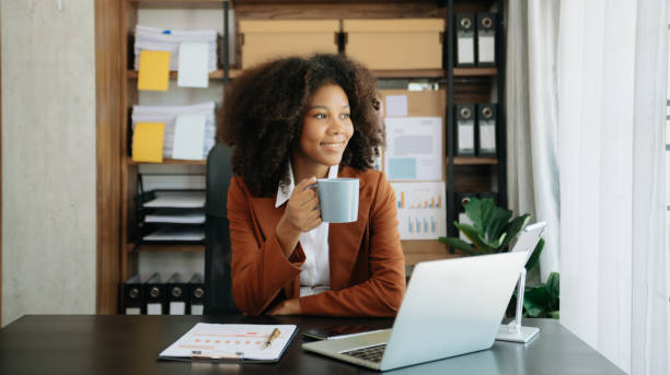 istock African Woman freelancer is working her job on computer tablet and laptop Doing accounting analysis report real estate investment data, Financial 2151385528