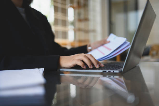 istock Young businessman in black suit checking financial reports at modern workplace 2151388103