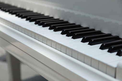 Close-up of a white piano keyboard with two lights, shot diagonally, no one playing.