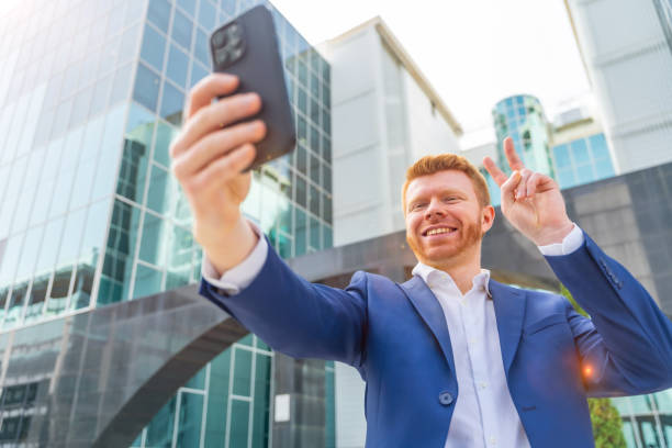 istock Businessman gesturing success while taking selfie outdoors 2151389002