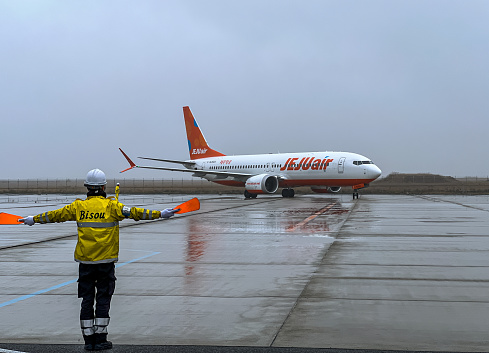 Osaka, Japan- March 25, 2024: Aviation Marshall guiding  Jeju airplane at the airport. Ground Crew in the signal vest.