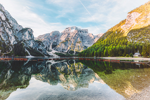 Beautiful lake in nature and summer with a wooden pier, orange boats and mountain reflection during sunrise at a beautiful turquoise water lake Lago di Braies, Trentino Alto Adige, South Tirol, European Alps, Italia, South Europe