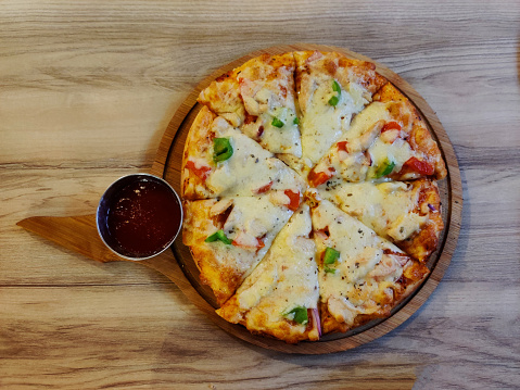 Top view of Chicken pizza on a wooden background. Tasty traditional pizza on board.