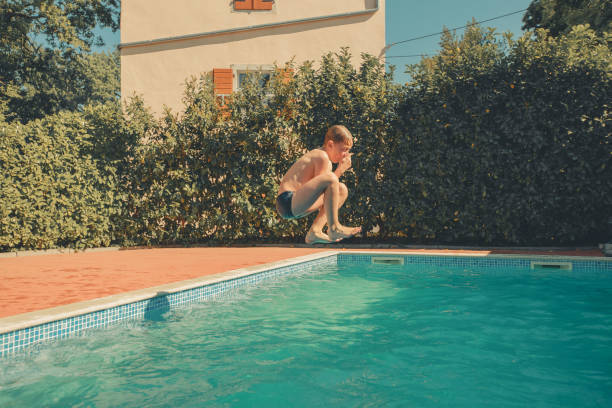 istock Boy jumps into outdoor swimming pool 2151400555