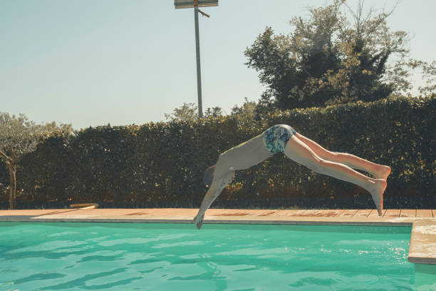 istock Young boy dives into outdoor swimming pool 2151400632