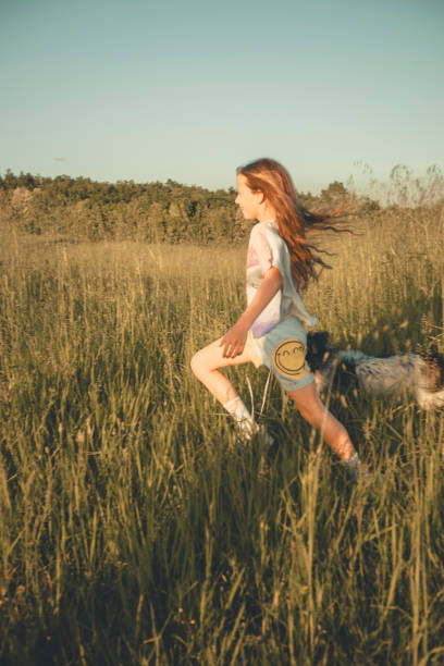 istock Young girl runs through field with dog 2151400806