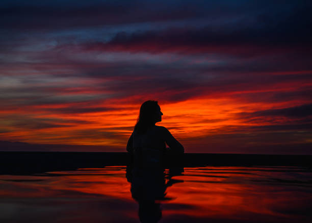 Female in belly dancing costume dancing in desert at sunset