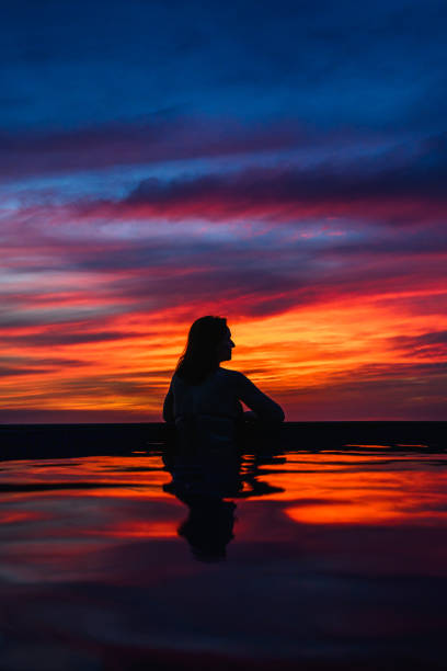 Woman reflected in swimming pool at dusk