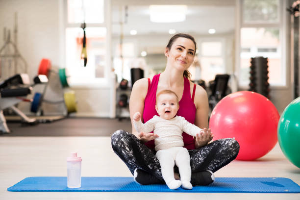istock Portrait of new mom on group exercise class in gym. Moms staying active while boding with babies. 2151404973