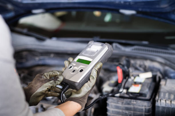istock Female auto mechanic using diagnostic tool, scanner, running diagnostic on car. Beautiful woman working in a garage, wearing blue coveralls. 2151405306