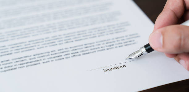 istock Hand holds pen and signs agreement contract on the table. 2151408534