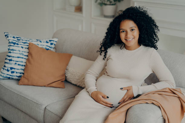 istock Expectant mother glowing with maternal grace while resting on a homely couch. 2151412612
