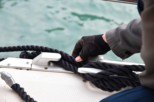 Man hands and yacht rope cleat, yacht detail. Yachting