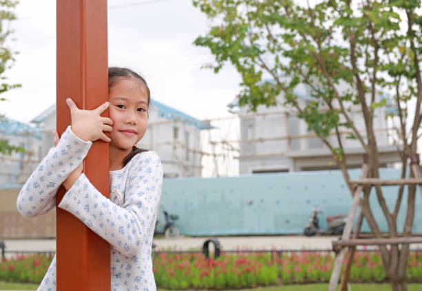 Asian young girl kid hugging the pole at playground.