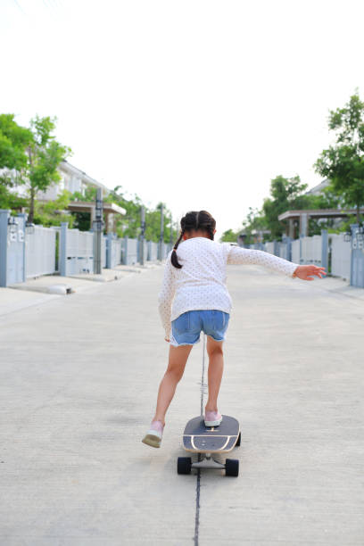 istock Kid riding on skateboard outdoors at the street. Back view 2151416837