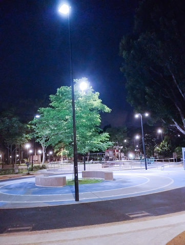 well-lit children's playground at night with a tree in the middle