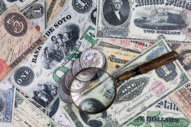 istock Old US banknotes and silver certificates with silver dollar coins and magnifying glass 2151427197