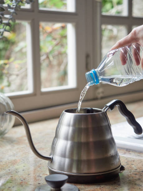 istock Pouring water from a plastic bottle into a kettle on the kitchen countertop. 2151430392