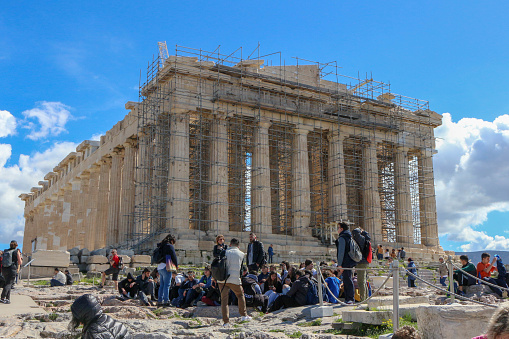 Athens, Greece - March 13, 2024: Amidst scaffolding and bustling activity, the Parthenon, an enduring symbol of classical architecture, undergoes meticulous restoration. Skilled craftsmen and engineers work tirelessly to preserve the magnificence of this ancient marvel, carefully repairing weathered marble and reinforcing delicate columns. Despite the construction, the timeless elegance of the Parthenon still shines through, its majestic silhouette standing as a testament to the ingenuity and resilience of ancient civilizations. As visitors observe the ongoing restoration efforts, they are reminded of the enduring legacy and cultural significance of this iconic monument.