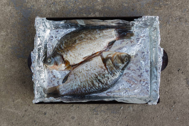 Peeled carcasses of fish (crucian carp) are lying on a deco. Ready to bake in a grill