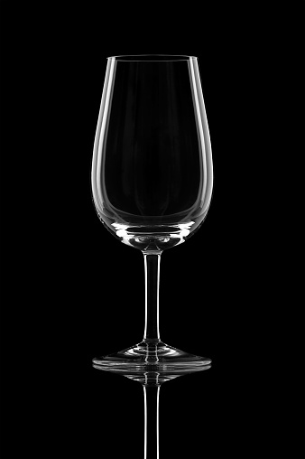 Empty crystal brandy glass on a dark black background in dramatic lighting. Isolated fine dining drinking glass bar & restaurant