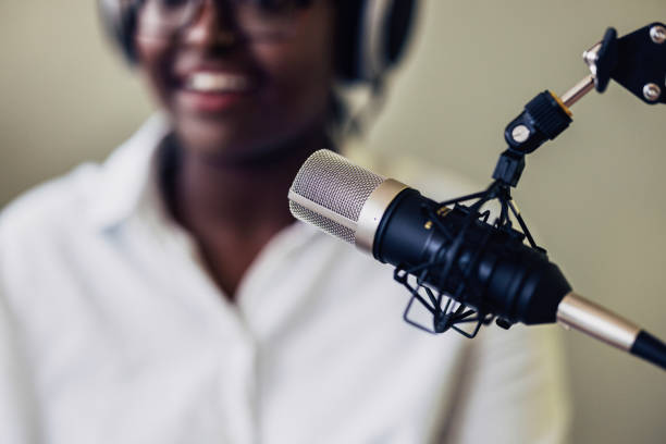 Focused young man speaking into a condenser microphone in a soundproof studio, captured with close-up to highlight vocal activity in a podcast setting