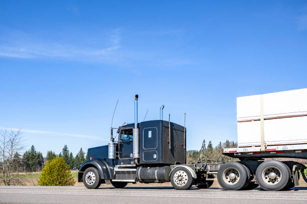 istock Extended cab black classic big rig semi truck transporting cargo on flat bed semi truck driving on the flat h road 2151452436