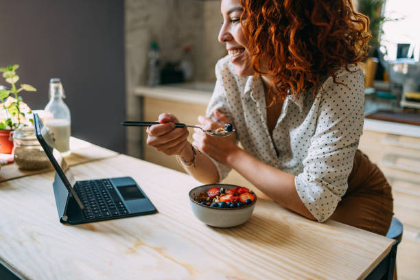 istock Young Woman Enjoying Breakfast While Working on Laptop 2151453406